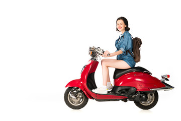 Fototapeta na wymiar full length view of girl sitting on red scooter isolated on white