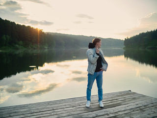 Fototapeta na wymiar The guy posing against the backdrop of the lake during sunset.