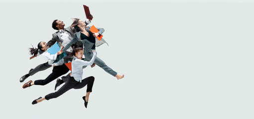 Happy office workers jumping and dancing in casual clothes or suit with folders isolated on studio background. Business, start-up, working open-space, motion and action concept. Creative collage.