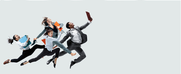 Happy office workers jumping and dancing in casual clothes or suit with folders isolated on studio...