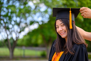 Long haired female students wearing black ruffle dresses expressing joy on graduation at the...
