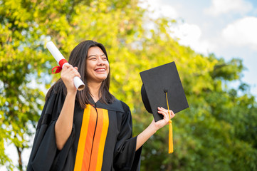 Long haired female students wearing black ruffle dresses expressing joy on graduation at the...