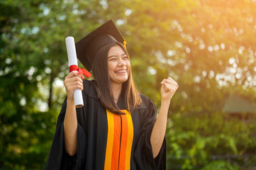Long haired female students wearing black ruffle dresses expressing joy on graduation at the...