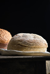 baked round white wheat bread on a textile towel, wooden old table