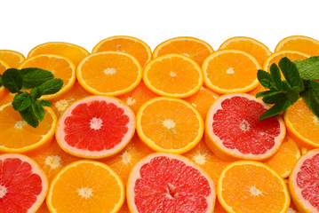 Slices of oranges and a grapefruits and mint as a background.
