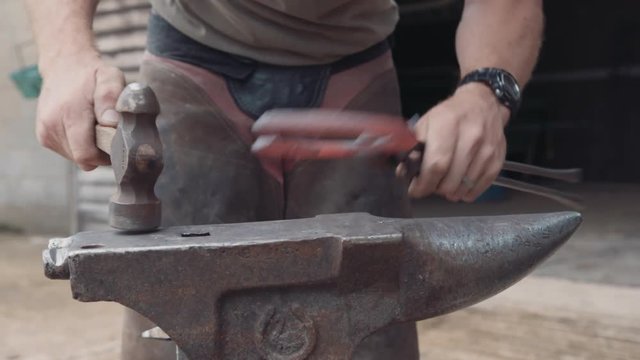Farrier blacksmith shaping horse shoe with hammer