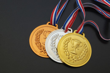 Gold, silver and bronze medal with ribbons on black board