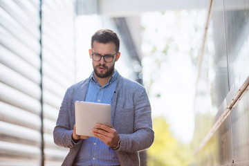 Portrait of handsome young businessman using digital tablet