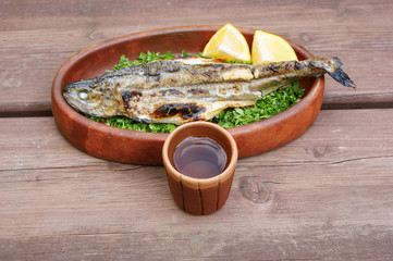 handmade clay glass. Handmade filled clay cup on the background of a clay plate with grilled fish