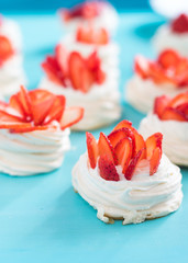 Beautiful pavlova cakes with strawberries on a blue background. Selective focus. Tasty sweet breackfast. Wedding morning. Meringue with cream.