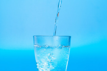 Close up pouring purified fresh drink water from the bottle on table