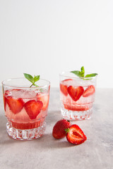 strawberry lemonade with ice and mint in glass on white background. Cold detox water as summer refreshing drink. Copy space