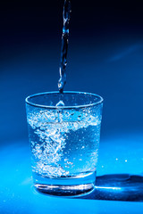 Close up pouring purified fresh drink water from the bottle on table