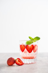 Fresh lemonade with ice, mint and strawberry in glass on white table background. Cold refreshing summer drink. Sparkling glasses with berry cocktail. Copy space