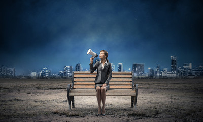 Business woman with megaphone on wooden bench