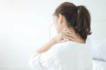 Fototapeta premium Asian women wear white pajamas in the bedroom. She has pain in the neck area.Do not focus on the main object of this image.
