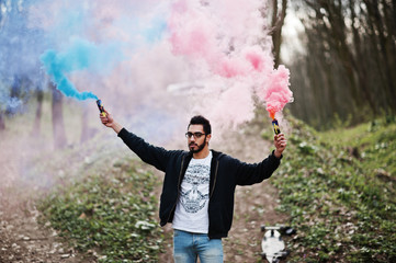 Street style arab man in eyeglasses hold hand flare with red and blue smoke grenade bomb.