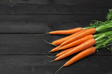 Bunch of fresh carrots with green leaves on wooden table