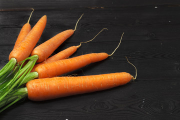 Bunch of fresh carrots with green leaves on wooden table