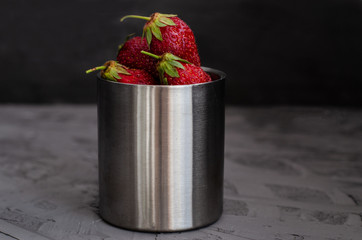 Fresh summer ripe strawberries in a cup on a gray concrete background