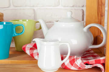 Kitchen utensils and dishware on wooden shelf