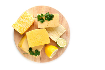 Variety of cheeses stacked on a cutting Board, on a white background with lemon and lime.
