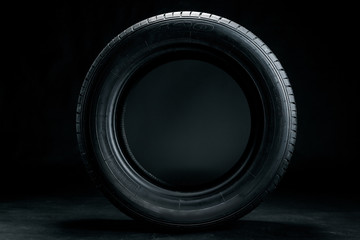 Brand new modern car tyre on a black background. Studio shot © NewFabrika