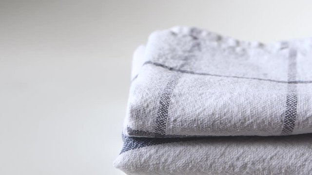 Hand takes kitchen towels from stack folded on white background with copy space