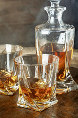 A bottle of cognac and glass on a brown wooden background. Brandy