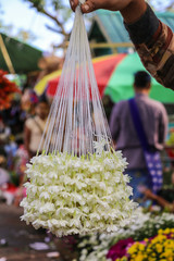 People walking along the street selling garland of fresh flowers, Hongsa(Bago), Myanmar.