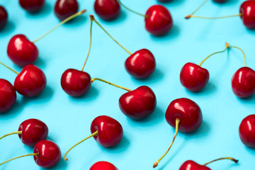 Red ripe cherry beries on blue background. Cherry pattern. Flat lay. Healthy food concept.