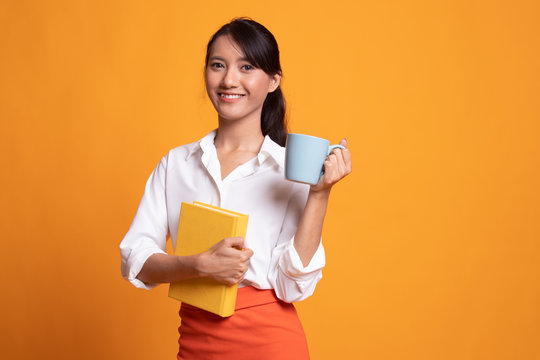 Young Asian woman with a book and cup of coffee.