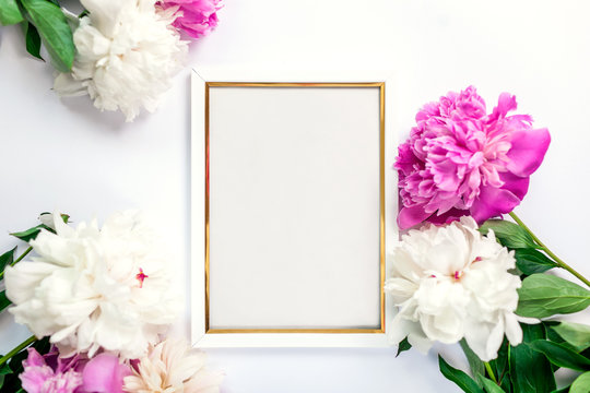 White and golden wooden frame decorated with peonies flowers. Mockup, top view, space