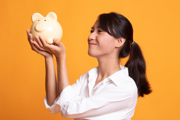 Fototapeta na wymiar Young Asian woman kiss a pink coin bank.