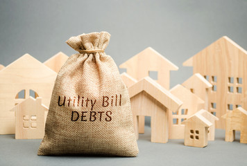 Money bag with the words Utility bill debts and wooden houses. Fines and penalties for failure to...