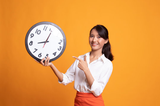 Young Asian woman point to a clock.