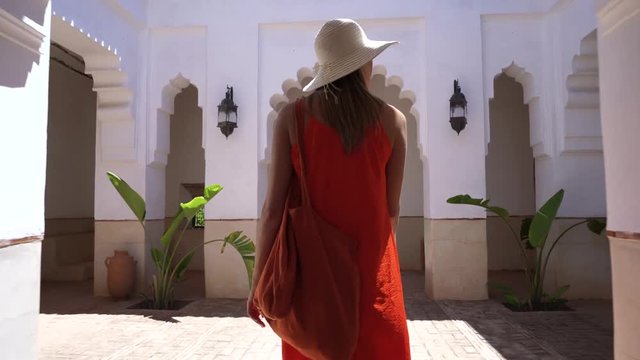 Stunning woman in bright dress exploring Moroccan riad and gardens