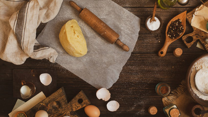 Overhead shot of homemade dough and rolling pin on baking paper on rustic table 
