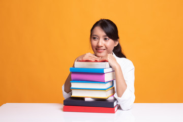 Happy young Asian woman read a book with books on table.
