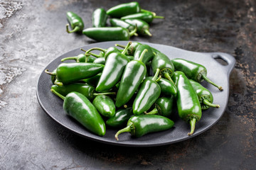 Fresh raw green hot jalapeno chili as closeup on a bowl with copy space