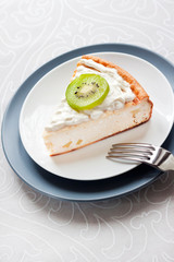 Homemade cottage cheese cake with kiwi fruit and cream on a plate
