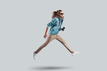 Music makes you fly. Full length of handsome young man hovering against grey background