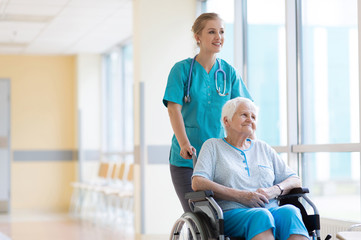 Fototapeta na wymiar Senior woman in wheelchair with nurse in hospital