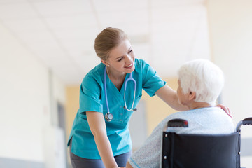 Senior woman in wheelchair with nurse in hospital