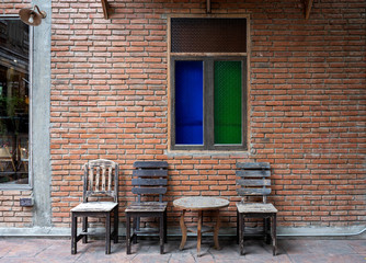 Fototapeta na wymiar Antique set of wooden table and chairs with the classic color glass window on the old brick wall interior vintage style