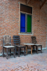 Fototapeta na wymiar Antique set of wooden table and chairs with classic color glass window on the old brick wall interior vintage style