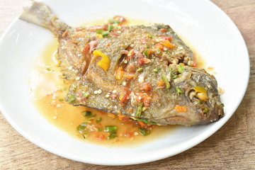 deep fried white pomfret dressing spicy sauce on plate