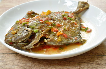 deep fried white pomfret dressing spicy sauce on plate