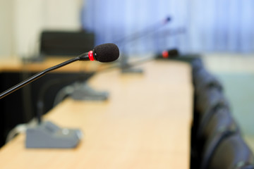 conference microphones in a meeting room is blurred in the  background.