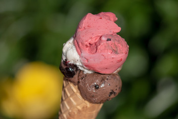 Ice cream in a cone with green Background. Flavour: Raspberry, Stracciatella and chocolate